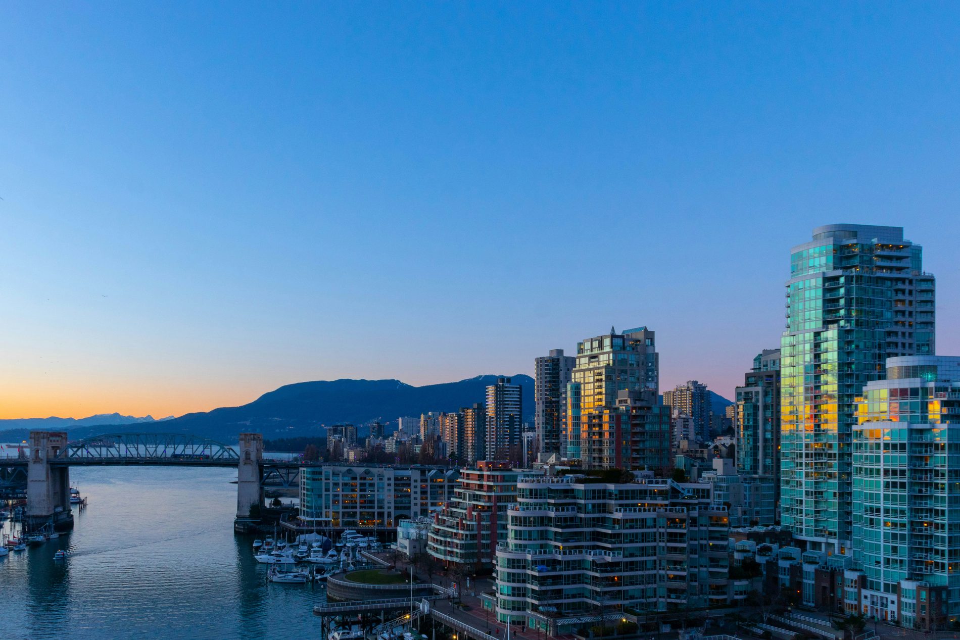 Vancouver skyline at dusk over False Creek, with the Burrard Bridge and the North Shore mountains